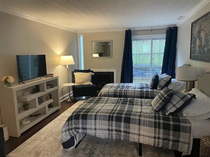 Tidy bedroom with two plaid-covered beds, carpet and a window seating area