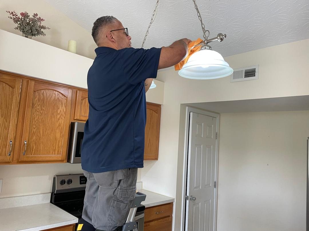 American Maids team member carefully cleaning a kitchen light fixture