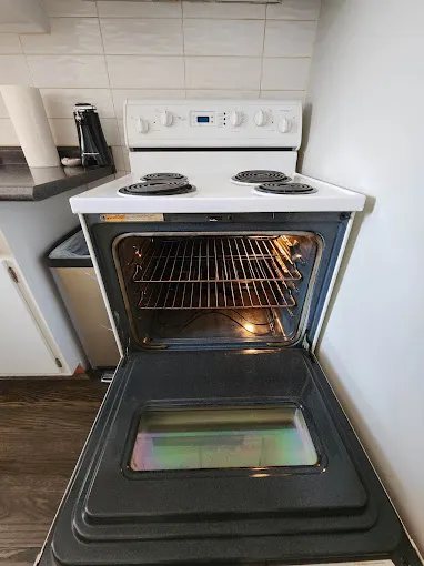 Open oven showing the interior racks beneath a white electric stovetop