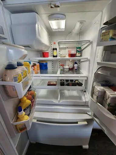 Open refrigerator with wiped shelves, drawers and food stored inside