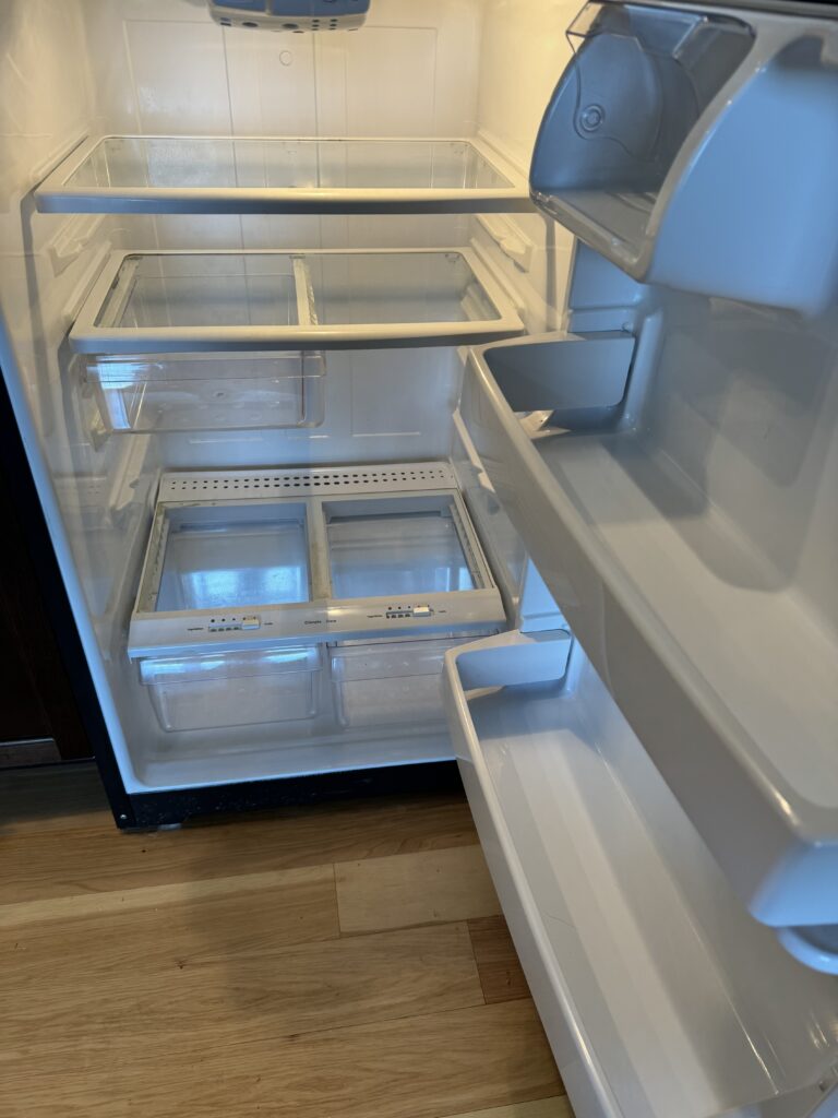 The interior of a stainless steel fridge after deep cleaning, with spotless shelves and crisp white surfaces.