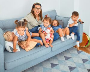 Happy family with four young children sitting on a sofa in Mason, Ohio, illustrating the need to ask the right questions when hiring a house cleaner.